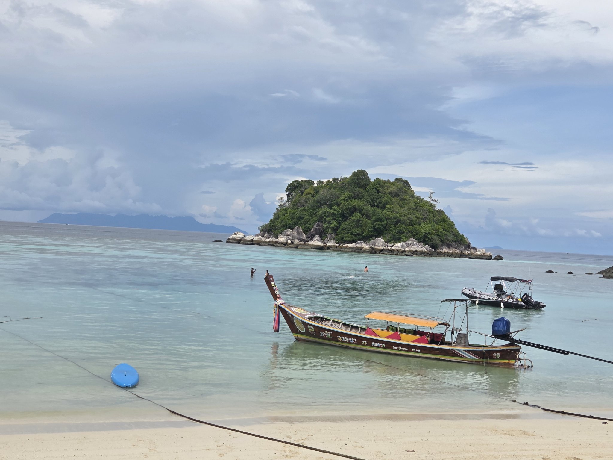 A longtail boat anchored in shallow turquoise water near Koh Lipe